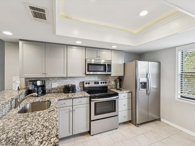 214 Meadow Ln Unit 214, Oldsmar, FL 34677 - kitchen with appliances with stainless steel finishes, gray cabinetry, a raised ceiling, decorative backsplash, and recessed lighting