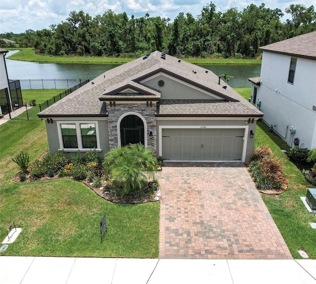12646 Oak Hill Way, Parrish, FL 34219 - view of front facade featuring a water view, decorative driveway, an attached garage, a shingled roof, and stucco siding