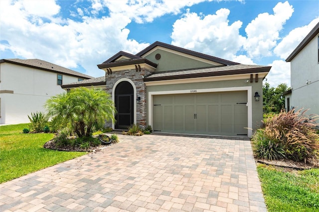 12646 Oak Hill Way, Parrish, FL 34219 - view of front of property with stucco siding, decorative driveway, stone siding, a garage, and a front yard