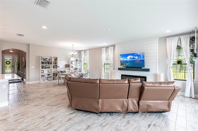 12646 Oak Hill Way, Parrish, FL 34219 - living room with arched walkways, a chandelier, a large fireplace, recessed lighting, and light wood-style floors
