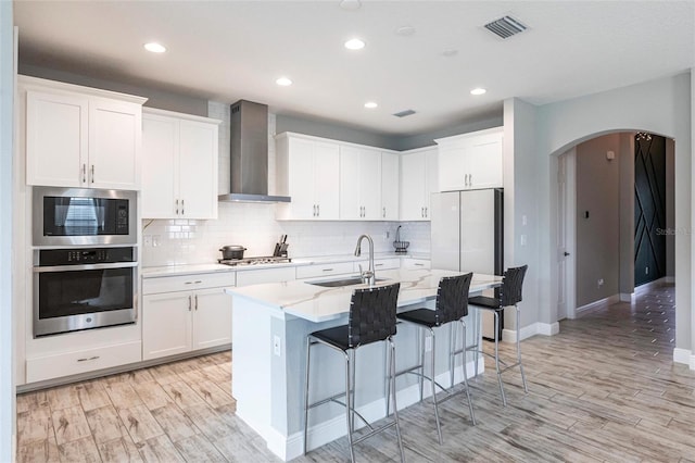 12646 Oak Hill Way, Parrish, FL 34219 - kitchen featuring stainless steel appliances, wall chimney range hood, arched walkways, a kitchen breakfast bar, and backsplash