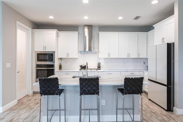 12646 Oak Hill Way, Parrish, FL 34219 - kitchen featuring appliances with stainless steel finishes, wall chimney exhaust hood, light wood-style flooring, backsplash, and recessed lighting