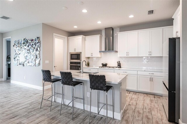 12646 Oak Hill Way, Parrish, FL 34219 - kitchen featuring appliances with stainless steel finishes, wall chimney range hood, light wood-style flooring, light countertops, and decorative backsplash