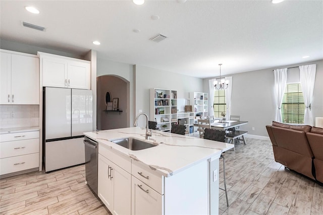 12646 Oak Hill Way, Parrish, FL 34219 - kitchen with freestanding refrigerator, stainless steel dishwasher, open floor plan, a chandelier, and white cabinets