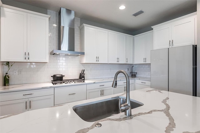 12646 Oak Hill Way, Parrish, FL 34219 - kitchen with wall chimney range hood, stainless steel gas stovetop, freestanding refrigerator, white cabinetry, and recessed lighting