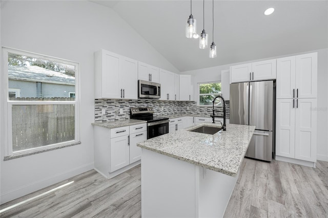 2859 38th Ave N, Saint Petersburg, FL 33713 - kitchen featuring appliances with stainless steel finishes, lofted ceiling, light wood-type flooring, light stone counters, and white cabinets
