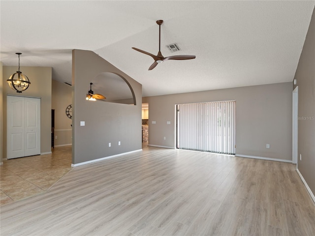 37147 Foxrun Pl, Zephyrhills, FL 33542 - unfurnished living room featuring a ceiling fan, vaulted ceiling, light wood-type flooring, and a chandelier