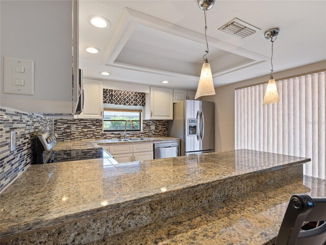 37147 Foxrun Pl, Zephyrhills, FL 33542 - kitchen with stainless steel appliances, a tray ceiling, decorative backsplash, hanging light fixtures, and recessed lighting