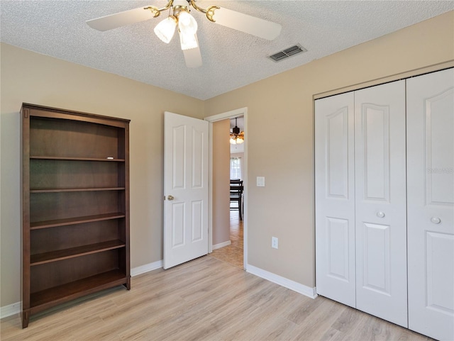 37147 Foxrun Pl, Zephyrhills, FL 33542 - unfurnished bedroom featuring light wood-style floors, a textured ceiling, a closet, and a ceiling fan