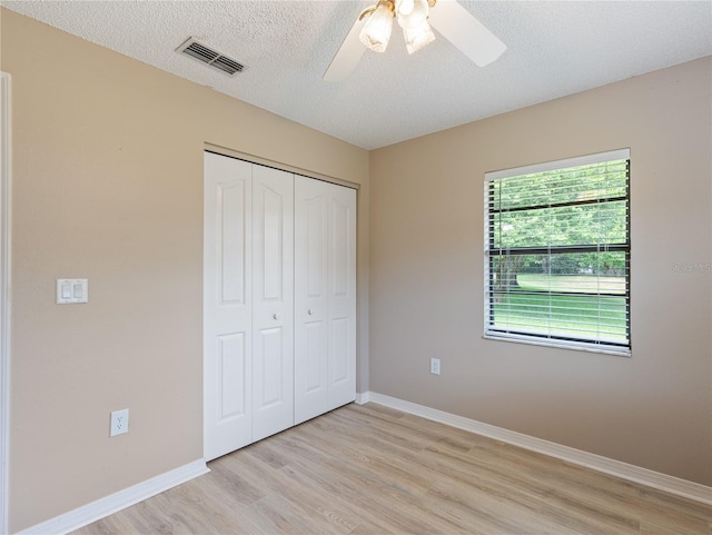 37147 Foxrun Pl, Zephyrhills, FL 33542 - unfurnished bedroom featuring light wood-style floors, a closet, a ceiling fan, and a textured ceiling