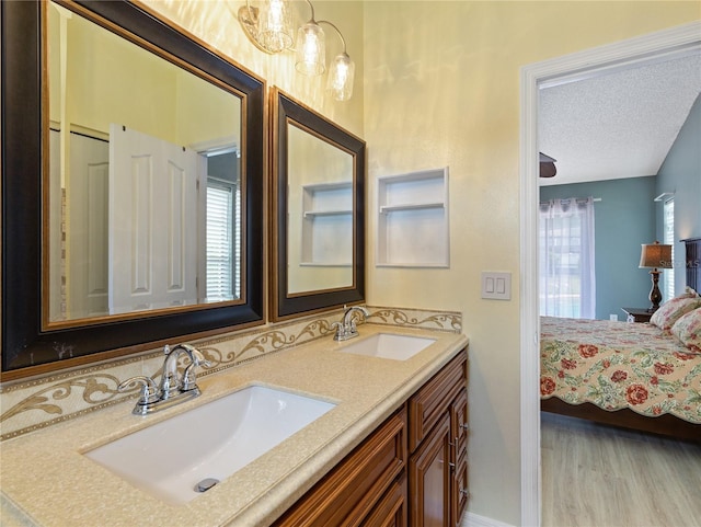 37147 Foxrun Pl, Zephyrhills, FL 33542 - ensuite bathroom featuring double vanity, a textured ceiling, and wood finished floors
