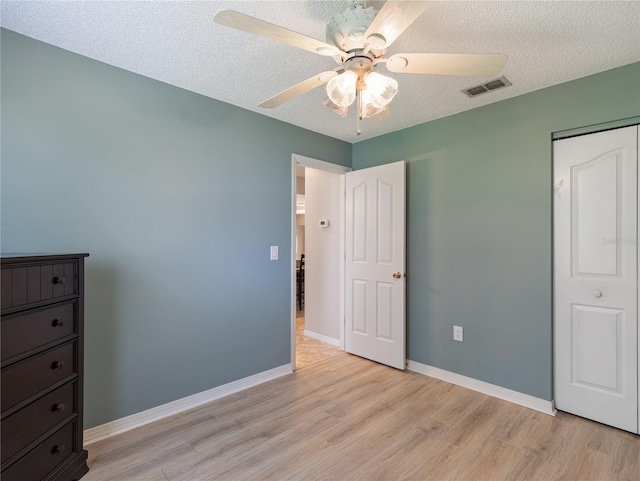 37147 Foxrun Pl, Zephyrhills, FL 33542 - unfurnished bedroom featuring light wood finished floors, a textured ceiling, and ceiling fan