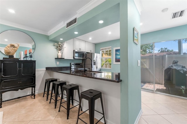 2809 W Platt St Unit 6, Tampa, FL 33609 - kitchen with appliances with stainless steel finishes, light tile patterned flooring, white cabinetry, ornamental molding, and a breakfast bar area
