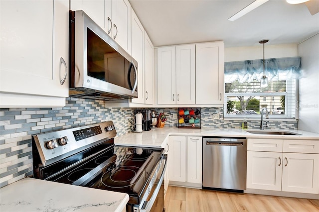 2700 Bayshore Blvd Unit 544, Dunedin, FL 34698 - kitchen featuring stainless steel appliances, white cabinets, backsplash, and light wood-style flooring