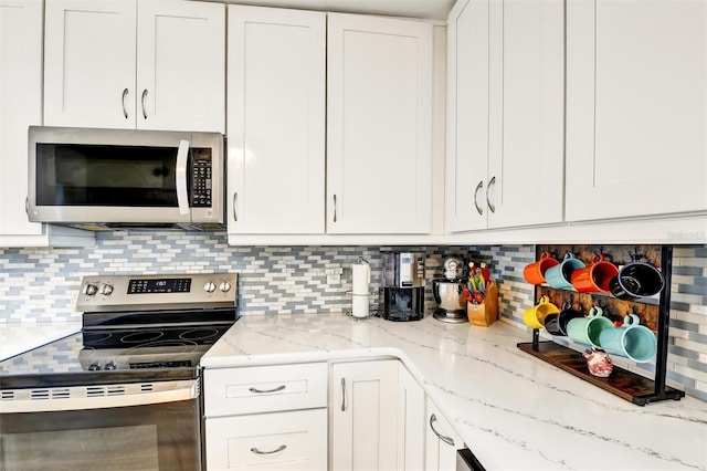 2700 Bayshore Blvd Unit 544, Dunedin, FL 34698 - kitchen with appliances with stainless steel finishes, white cabinetry, backsplash, and light stone countertops