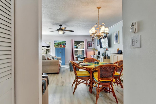 2700 Bayshore Blvd Unit 544, Dunedin, FL 34698 - dining room featuring light wood-style floors, a ceiling fan, a chandelier, a textured ceiling, and crown molding