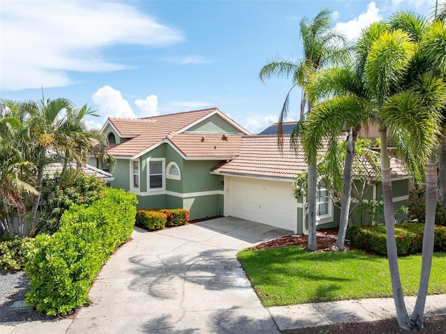 835 Symphony Isles Blvd, Apollo Beach, FL 33572 - view of front of house with a tiled roof, stucco siding, a garage, concrete driveway, and a front yard