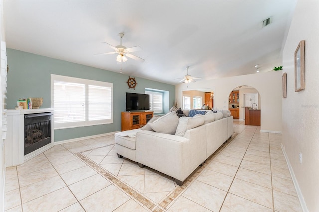 835 Symphony Isles Blvd, Apollo Beach, FL 33572 - living area with light tile patterned floors, a ceiling fan, a fireplace, and arched walkways