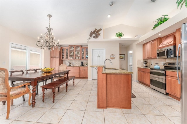 835 Symphony Isles Blvd, Apollo Beach, FL 33572 - kitchen featuring stainless steel appliances, a chandelier, lofted ceiling, tasteful backsplash, and an island with sink