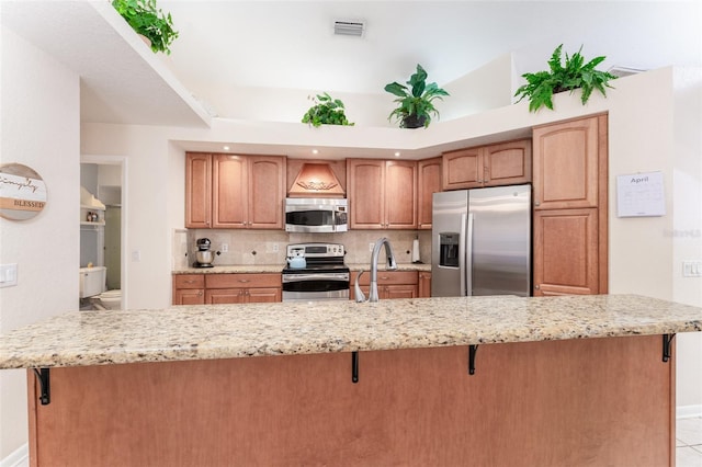 835 Symphony Isles Blvd, Apollo Beach, FL 33572 - kitchen featuring appliances with stainless steel finishes, a breakfast bar area, backsplash, and light stone counters