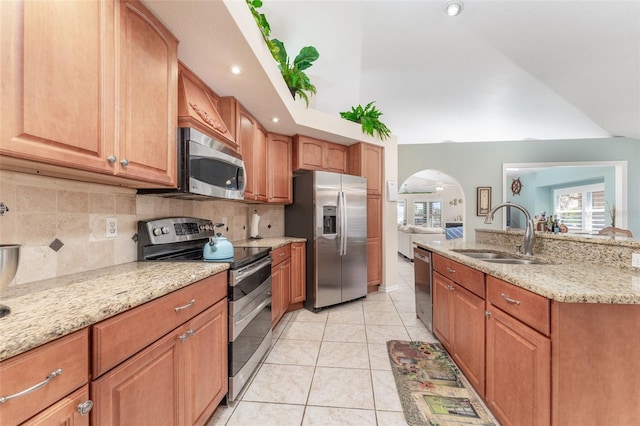 835 Symphony Isles Blvd, Apollo Beach, FL 33572 - kitchen featuring stainless steel appliances, arched walkways, tasteful backsplash, light stone countertops, and light tile patterned floors