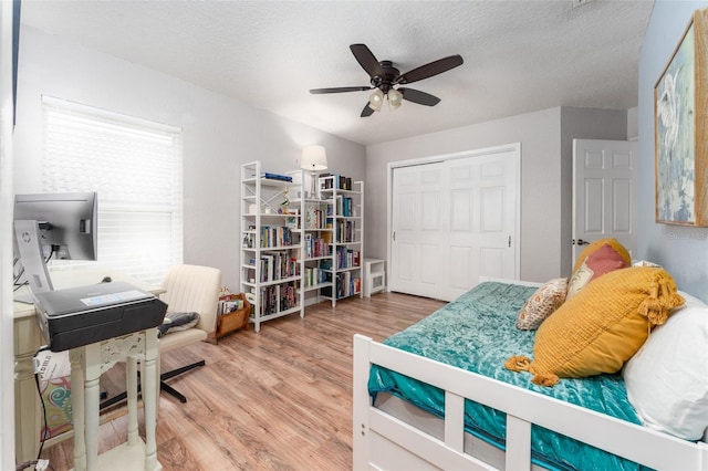 835 Symphony Isles Blvd, Apollo Beach, FL 33572 - bedroom featuring light wood finished floors, a closet, a ceiling fan, a desk, and a textured ceiling