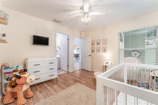 835 Symphony Isles Blvd, Apollo Beach, FL 33572 - bedroom with light wood finished floors, a ceiling fan, and a crib