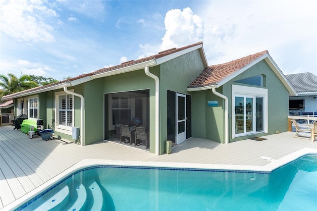 835 Symphony Isles Blvd, Apollo Beach, FL 33572 - back of house featuring a wooden deck, stucco siding, and an outdoor pool