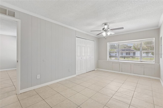 129 Magnolia Ave, Seffner, FL 33584 - unfurnished bedroom featuring ornamental molding, light tile patterned flooring, a textured ceiling, a closet, and a ceiling fan