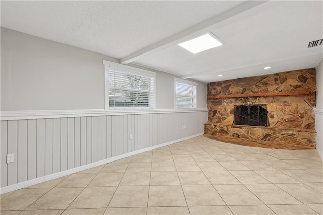 129 Magnolia Ave, Seffner, FL 33584 - unfurnished living room featuring a stone fireplace, a wainscoted wall, light tile patterned floors, and beam ceiling