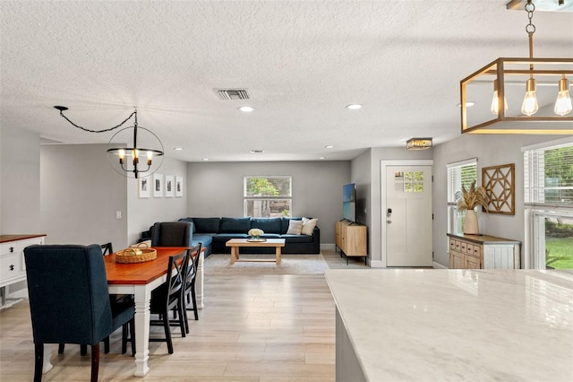 3135 W Varn Ave, Tampa, FL 33611 - dining area featuring a textured ceiling, light wood finished floors, plenty of natural light, a chandelier, and recessed lighting