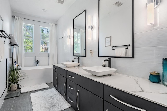 3210 W Horatio St Unit 9, Tampa, FL 33609 - bathroom with double vanity, a freestanding tub, and decorative backsplash
