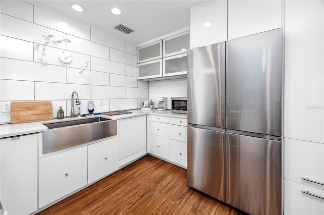 4050 4th St N Unit 116, Saint Petersburg, FL 33703 - kitchen featuring stainless steel appliances, backsplash, light countertops, wood finished floors, and white cabinets