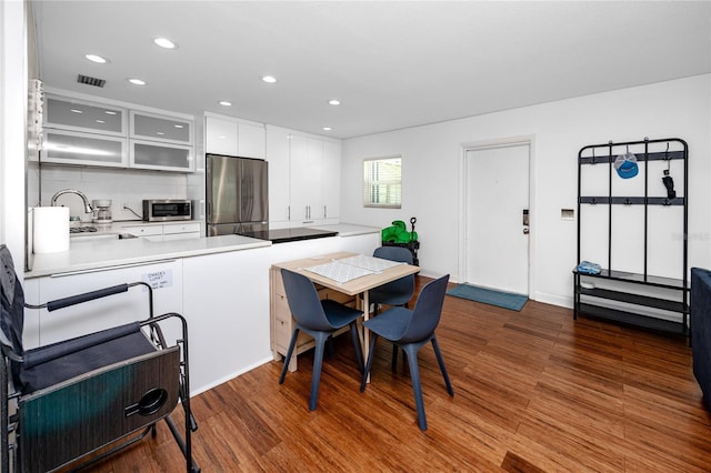 4050 4th St N Unit 116, Saint Petersburg, FL 33703 - kitchen featuring appliances with stainless steel finishes, dark wood finished floors, glass insert cabinets, white cabinets, and a peninsula