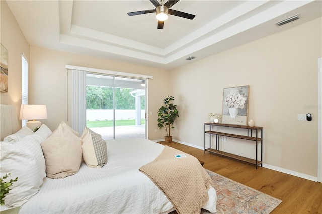 15412 Carrillon Estates Blvd, Tampa, FL 33625 - bedroom featuring access to exterior, a tray ceiling, wood finished floors, and ceiling fan
