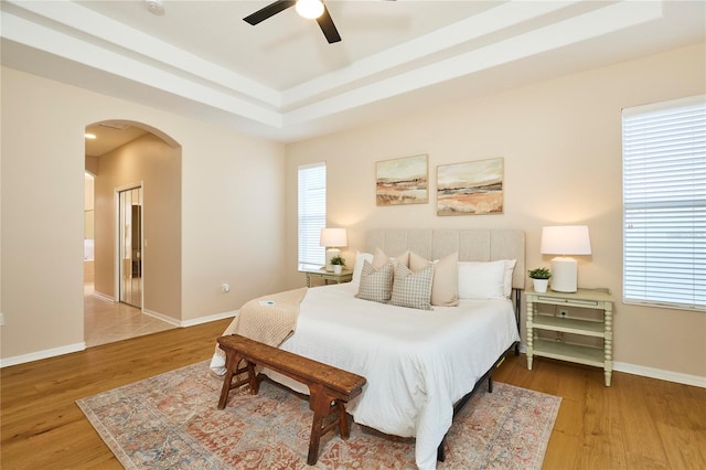 15412 Carrillon Estates Blvd, Tampa, FL 33625 - bedroom featuring arched walkways, wood finished floors, a raised ceiling, and ceiling fan