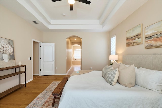 15412 Carrillon Estates Blvd, Tampa, FL 33625 - bedroom with arched walkways, a tray ceiling, wood finished floors, ceiling fan, and ensuite bath