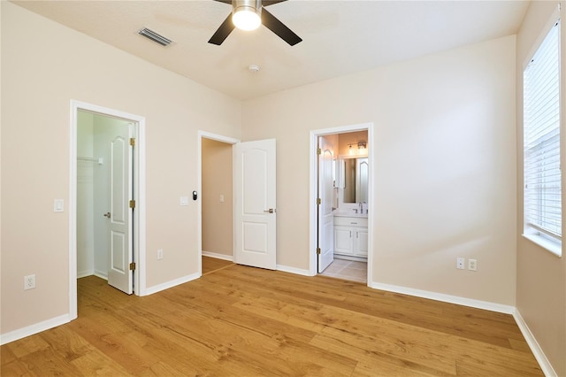 15412 Carrillon Estates Blvd, Tampa, FL 33625 - unfurnished bedroom with a walk in closet, light wood-type flooring, multiple windows, and ensuite bath