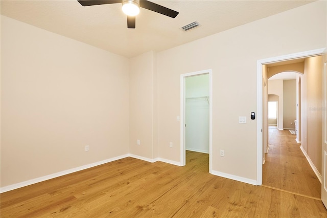 15412 Carrillon Estates Blvd, Tampa, FL 33625 - unfurnished bedroom featuring arched walkways, light wood-type flooring, a walk in closet, a closet, and a ceiling fan