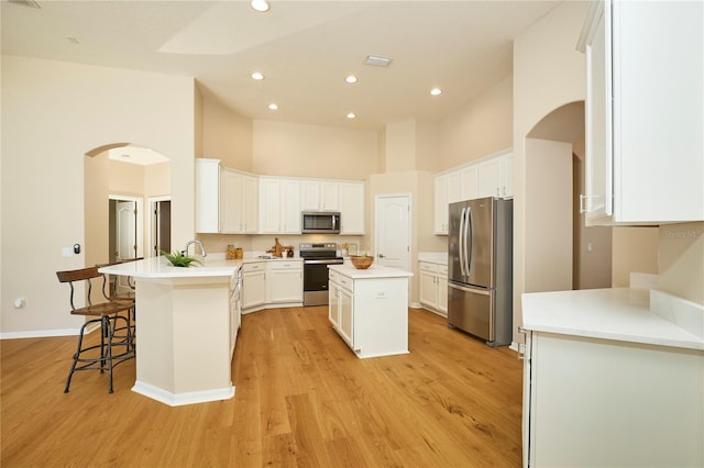 15412 Carrillon Estates Blvd, Tampa, FL 33625 - kitchen with appliances with stainless steel finishes, a high ceiling, a peninsula, arched walkways, and light wood-style flooring