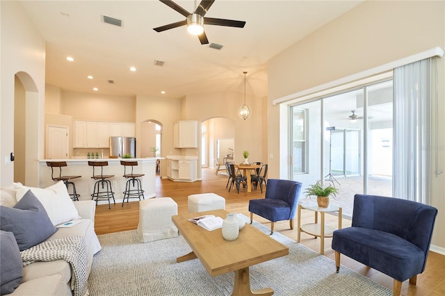 15412 Carrillon Estates Blvd, Tampa, FL 33625 - living room with arched walkways, a ceiling fan, light wood-style flooring, recessed lighting, and a towering ceiling