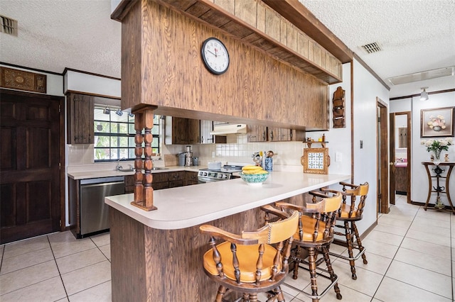 235 Old Welcome Rd, Lithia, FL 33547 - kitchen featuring a textured ceiling, stainless steel appliances, light countertops, light tile patterned flooring, and under cabinet range hood