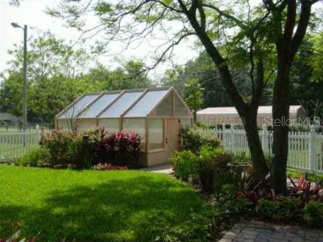 235 Old Welcome Rd, Lithia, FL 33547 - fenced yard featuring a greenhouse and an outdoor structure