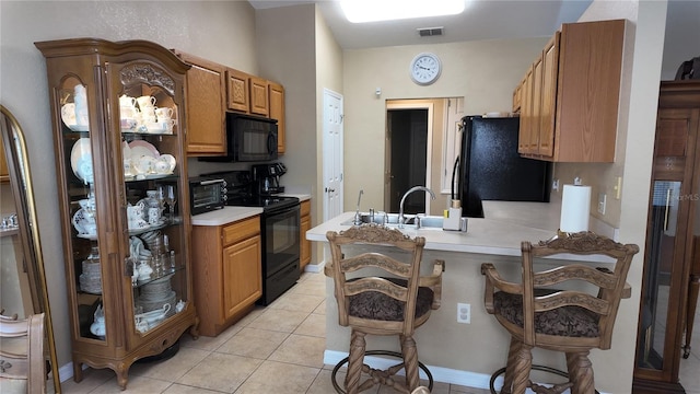 270 Planter Rd, Spring Hill, FL 34606 - kitchen featuring black appliances, a peninsula, light countertops, light tile patterned floors, and a breakfast bar area