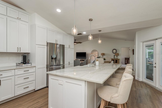 2800 Resnik Cir W, Palm Harbor, FL 34683 - kitchen with lofted ceiling, wood finished floors, recessed lighting, a breakfast bar, and white cabinetry