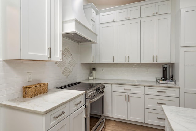 2800 Resnik Cir W, Palm Harbor, FL 34683 - kitchen with stainless steel range with electric stovetop, custom exhaust hood, tasteful backsplash, white cabinetry, and light stone counters
