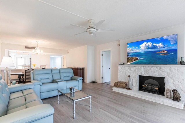 1150 Tarpon Center Dr Unit 1D, Venice, FL 34285 - living area featuring a chandelier, light wood-style flooring, a ceiling fan, a fireplace with raised hearth, and crown molding