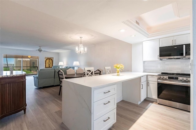 1150 Tarpon Center Dr Unit 1D, Venice, FL 34285 - kitchen featuring appliances with stainless steel finishes, a peninsula, white cabinetry, light wood finished floors, and recessed lighting