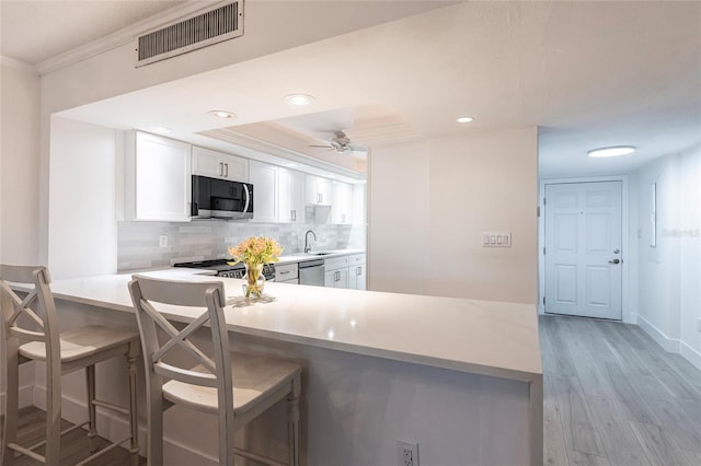 1150 Tarpon Center Dr Unit 1D, Venice, FL 34285 - kitchen featuring appliances with stainless steel finishes, crown molding, white cabinets, light countertops, and decorative backsplash