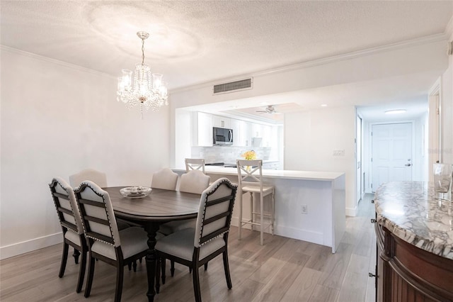 1150 Tarpon Center Dr Unit 1D, Venice, FL 34285 - dining room featuring a chandelier, light wood-style flooring, ornamental molding, and a textured ceiling